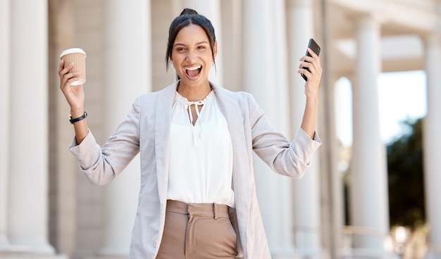 Mulher animada de café e negócios com telefone para motivação feliz comunicação e notificação na cidade da Alemanha Retrato de trabalhador corporativo em comemoração ao sucesso com smartphone e chá