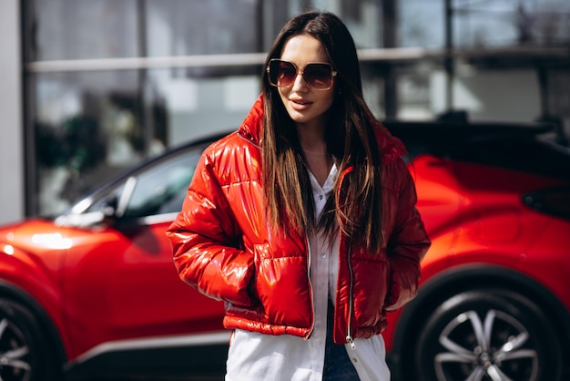 Mulher ao lado de seu novo carro vermelho