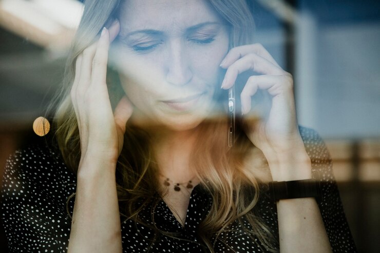 Foto mulher ao telefone com dor de cabeça