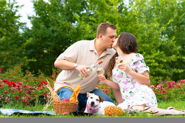 Mulher apaixonada e homem se beijando segurando taças de vinho, passeando com o cachorro casal de família romântico no ...