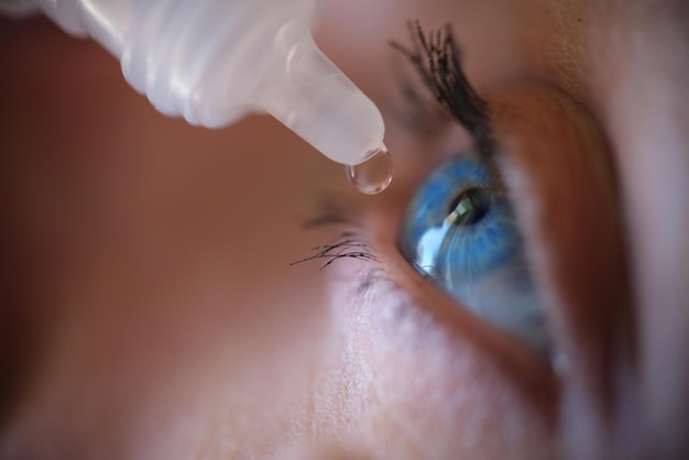 Mulher aplicando colírio para cuidados com os olhos e conceito de beleza