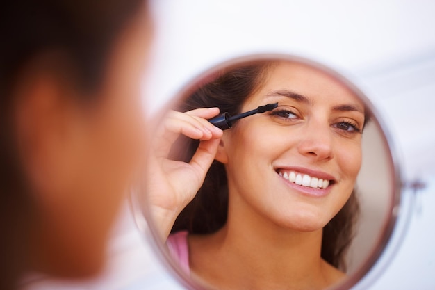 Mulher aplicando rímel Reflexo de uma linda mulher aplicando rímel