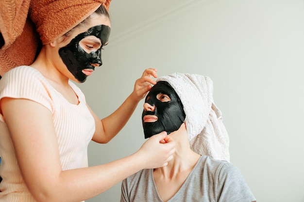 Mulher aplicar máscara de papel preto máscara de procedimentos cosméticos para cuidados com a pele para mulher jovem spa salão de beleza
