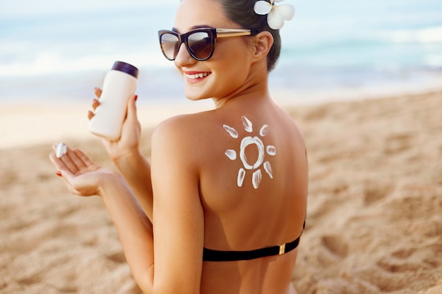 Foto mulher aplicar protetor solar nas costas bronzeada