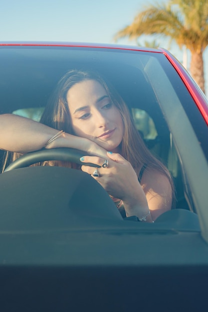 Mulher apoiada no volante dentro de um carro