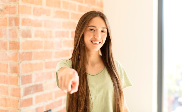 mulher apontando com o dedo, satisfeita, confiante, sorriso amigável, escolhendo você