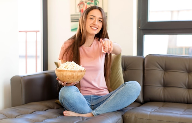 Mulher apontando para a frente com um sorriso satisfeito, confiante e amigável, escolhendo você