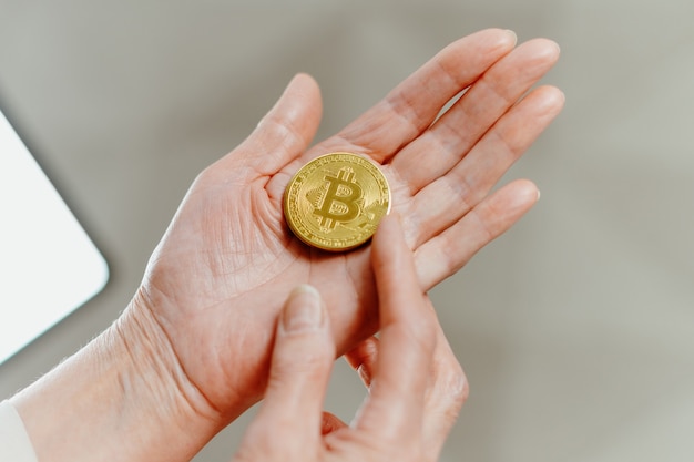 Mulher apontando para os bitcoins na palma da mão