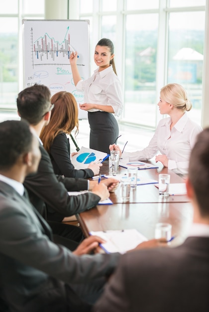 Mulher apontando para um gráfico crescente durante uma reunião.