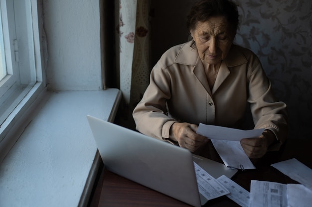 Mulher aposentada calculando suas contas domésticas