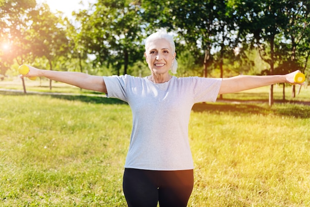 Foto mulher aposentada sorridente e positiva fazendo exercícios esportivos com halteres