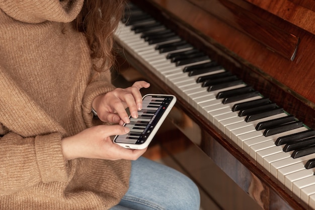 Mulher aprende a tocar piano no telefone, aula de música, treinamento online.