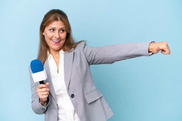 Mulher apresentadora de TV de meia-idade sobre fundo azul isolado, dando um polegar para cima gesto