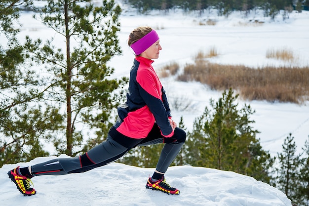Mulher apta a fazer exercícios de alongamento antes de correr ao ar livre. Treino de rua no inverno