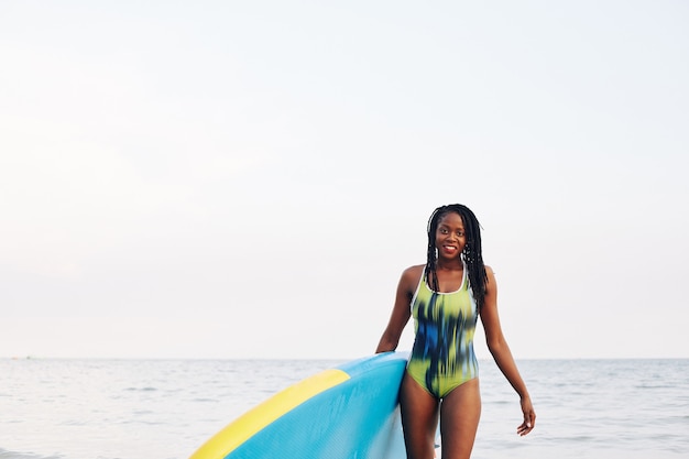 Mulher apta carregando prancha de surf