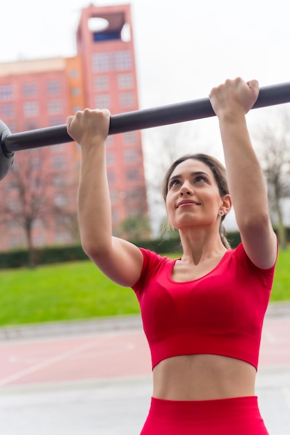 Mulher apta com roupa vermelha fazendo exercícios de braço em um parque fitness e conceito ativo saudável
