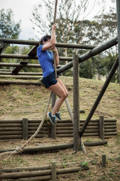 Mulher apta descendo a corda durante a pista de obstáculos