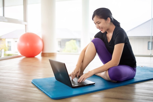 Mulher apta fazendo ioga e assistindo a tutoriais on-line no notebook