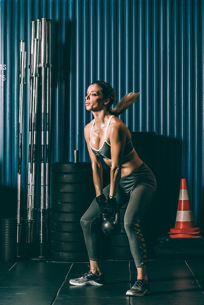 Mulher apta treinando malhando levantamento de kettlebell no ginásio