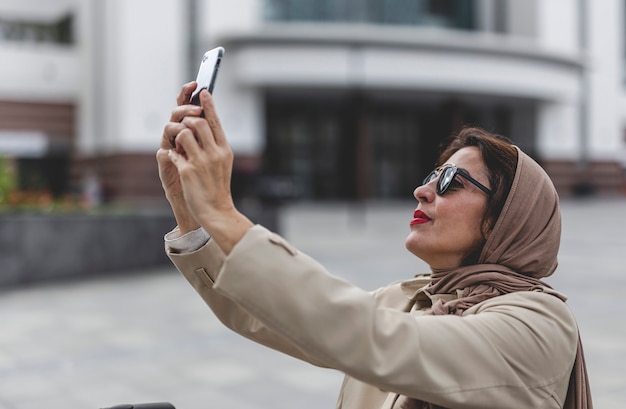 Mulher árabe atraente com hijab tomando uma selfie