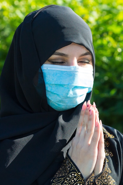 Mulher árabe com um lenço preto na cabeça e uma máscara médica protetora