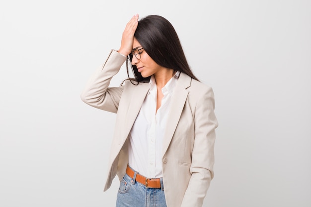 Mulher árabe do negócio novo isolada contra um fundo branco que esquece algo, batendo na testa com palma e fechando os olhos.