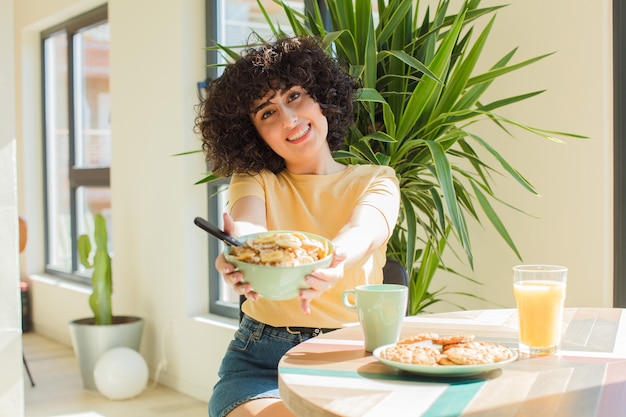 Mulher árabe jovem e bonita a tomar o pequeno-almoço em casa.