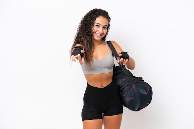 Mulher árabe jovem esportiva com bolsa esportiva isolada em fundo branco aponta o dedo para você enquanto sorri