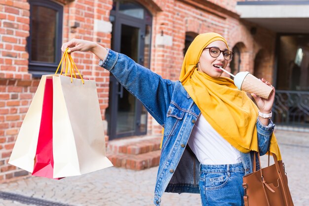 Mulher árabe muçulmana feliz com sacolas de compras