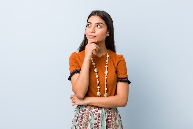 Mulher árabe nova que olha lateralmente com expressão duvidosa e cética.