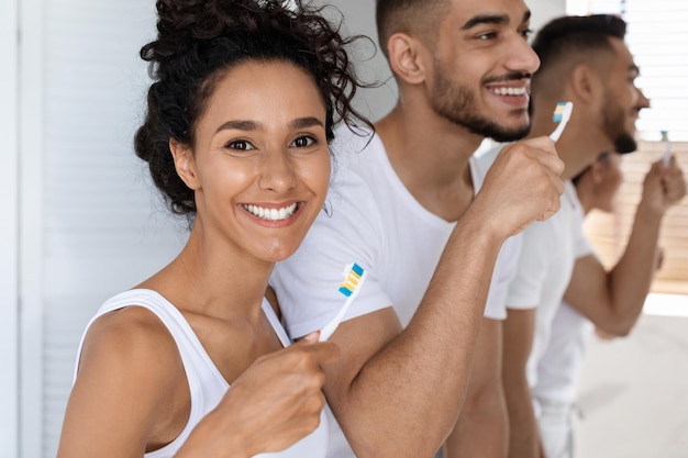 Foto mulher árabe sorrindo para a câmera enquanto escova os dentes com o marido de manhã