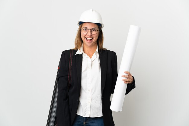 Foto mulher arquiteta de meia-idade com capacete e segurando plantas na parede isolada com expressão facial surpresa