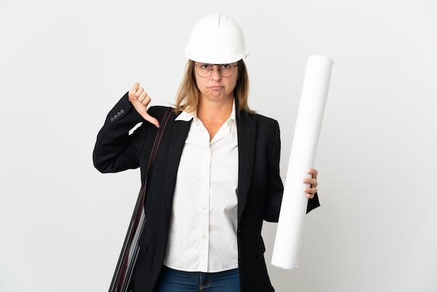 Mulher arquiteta de meia-idade com capacete e segurando plantas sobre fundo isolado mostrando o polegar para baixo com expressão negativa