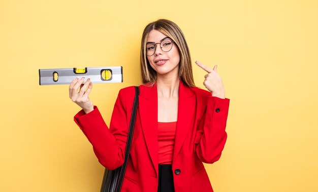 Mulher arquiteta sorrindo com confiança apontando para o próprio sorriso largo e mantendo um equilíbrio de nível