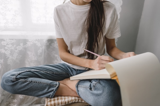 Mulher artista desenha em um caderno em casa