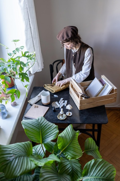 Mulher artista do milênio limpando em seu estúdio de arte colocando tintas e pincéis em um suporte de saco enrolado