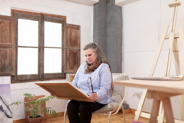 Mulher artista madura contemplando uma de suas obras