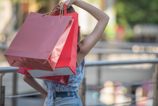 Mulher asian, segurando, bolsas para compras, e, levantado mãos cima