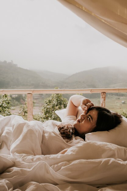 Mulher asiática acorda na tenda e olhando para o mountain view em vez do sol,