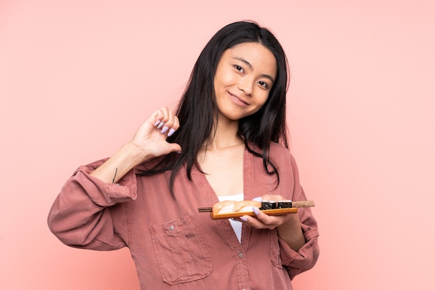 Mulher asiática adolescente comendo sushi isolado em uma rosa orgulhosa