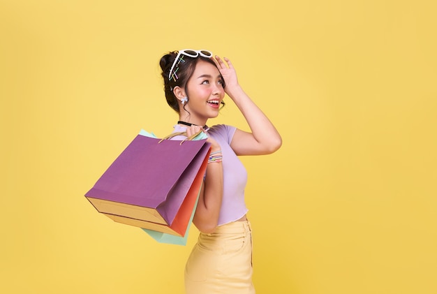 Mulher asiática adolescente feliz alegre curtindo as compras, ela está carregando sacolas de compras no centro comercial.