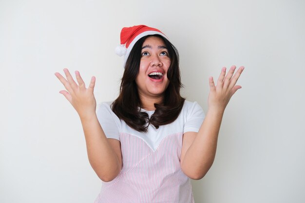 Foto mulher asiática adulta usando chapéu de natal e mostrando uma expressão feliz com os braços abertos