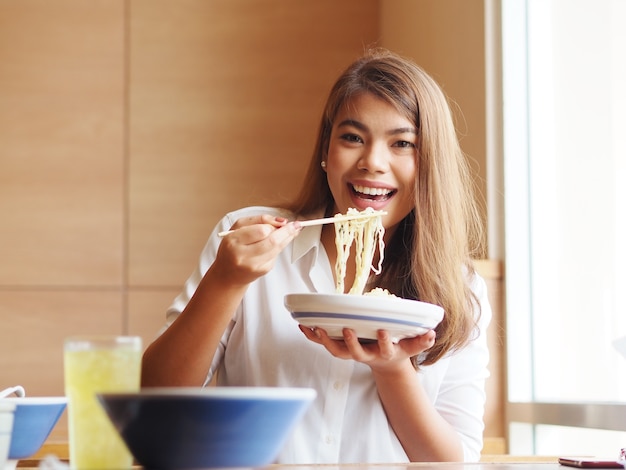 Mulher asiática alegre com macarronetes deliciosos no restaurante.