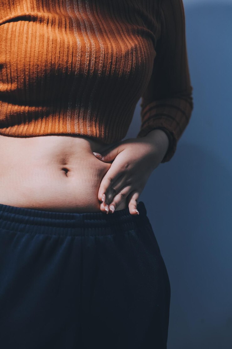 Foto mulher asiática apertando a gordura da barriga com a mão esquerda