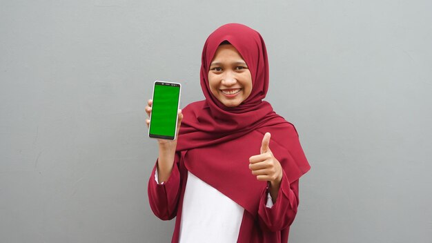 Mulher asiática apontando para o celular com tela verde