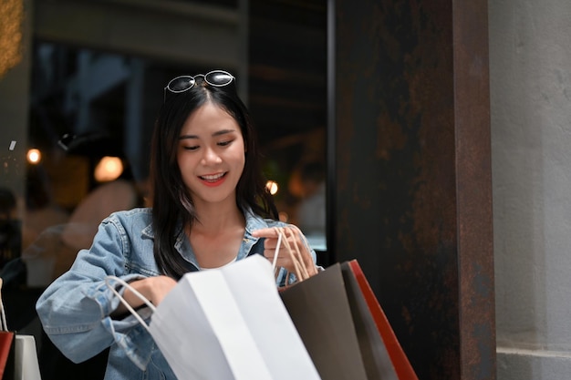 Mulher asiática atraente abrindo suas sacolas de compras verificando suas compras