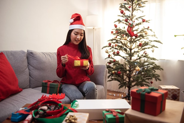 Mulher asiática atraente embrulhando uma caixa de presentes natal e festival de ano novo fundo árvore de natal