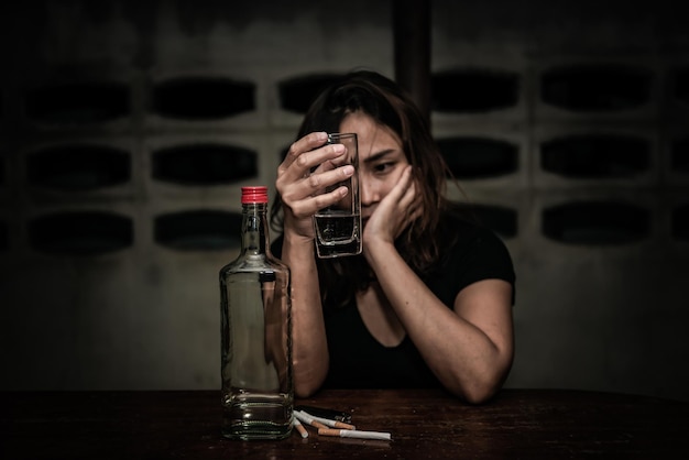 Mulher asiática bebe vodka sozinha em casa à noitepovo da tailândiaestressa o conceito de mulher bêbada