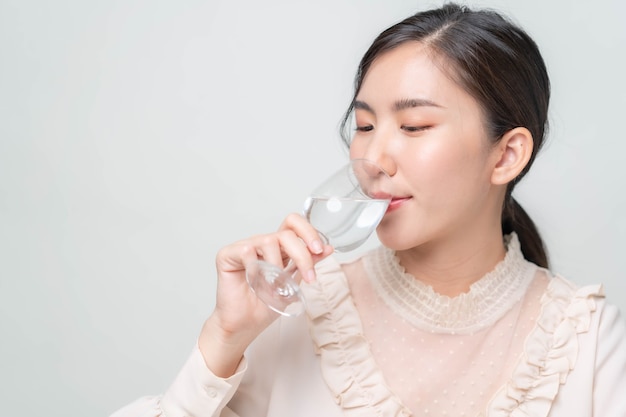 Mulher asiática bebendo água limpa em um fundo branco