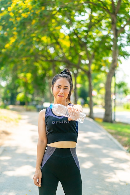 Mulher asiática bebendo água no sportwear